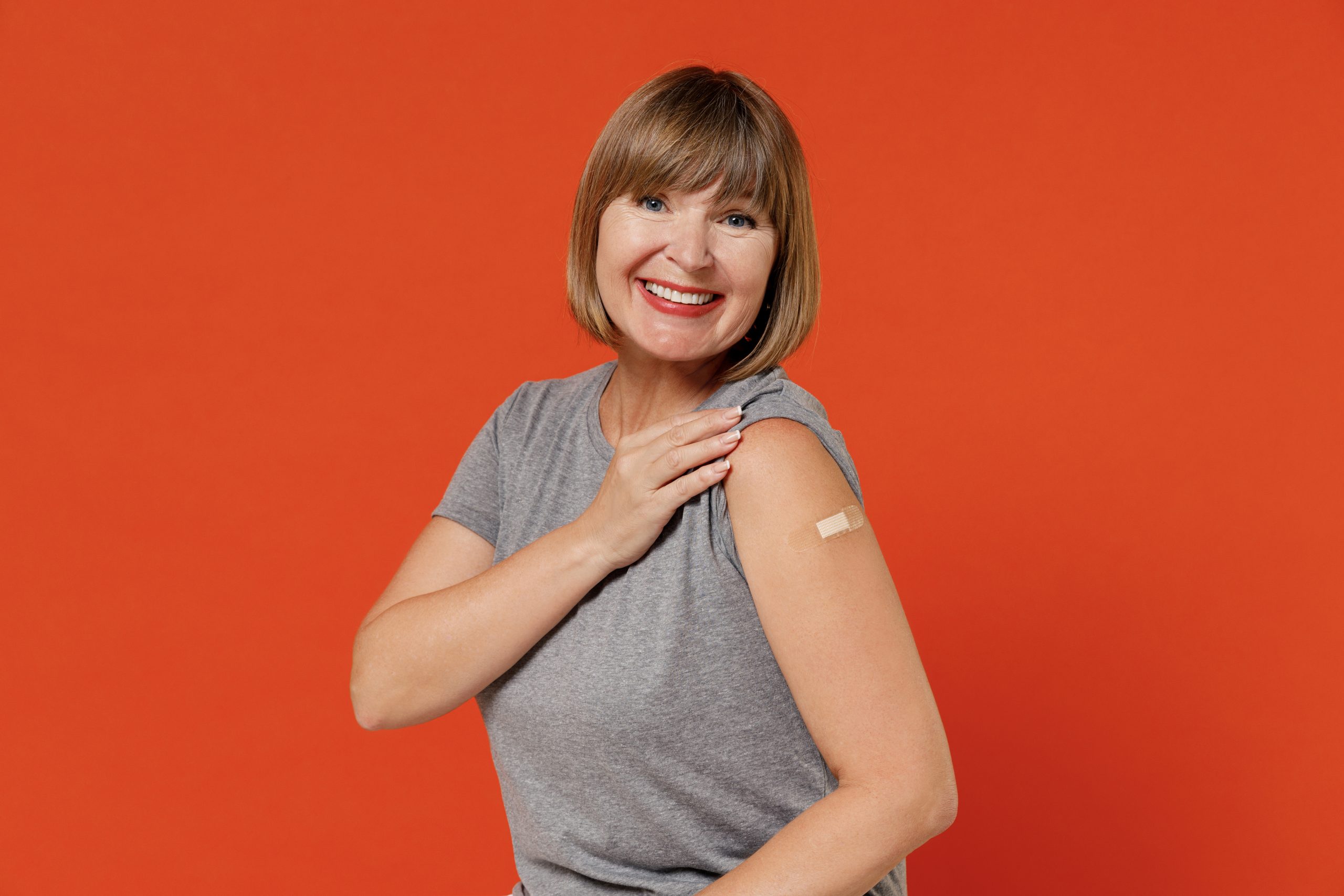 Woman in her 50s with a bandage on her arm, being vaccinated against COVID-19